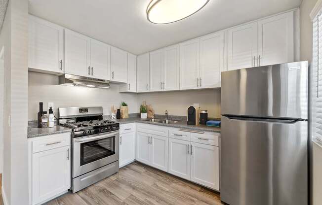 A modern kitchen with white cabinets and stainless steel appliances.
