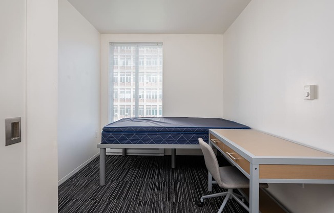 A bedroom with a bed, desk, and chair.