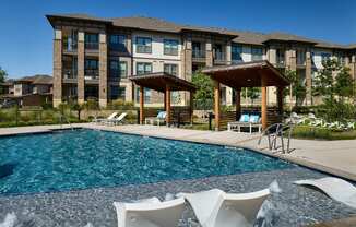 A large swimming pool in front of a building with a gazebo.