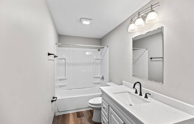 A white bathroom with a toilet, sink, and mirror.