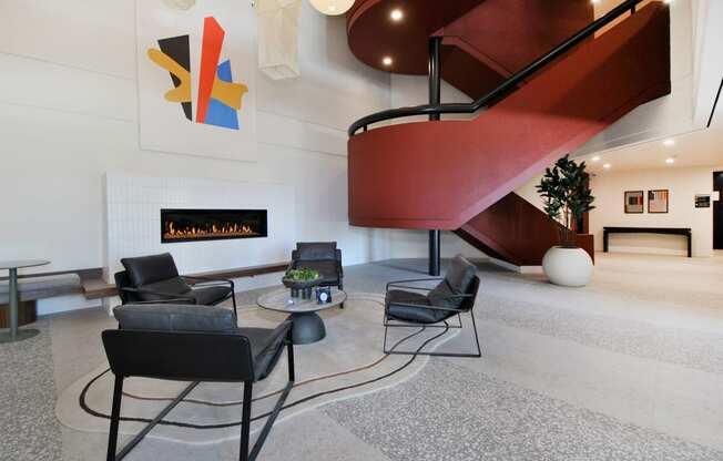 a living room with chairs and a fireplace and a spiral staircase