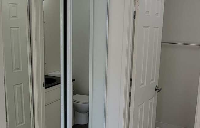 Carpeted bedroom with large mirrored door closet and private bathroom at Northwood Apartments in Upland, California.