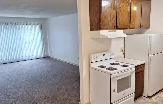 an empty kitchen with a white stove and refrigerator