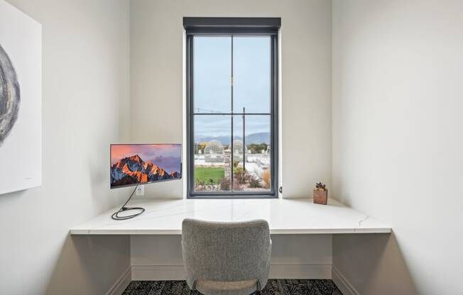 a desk with a computer and a window in a room