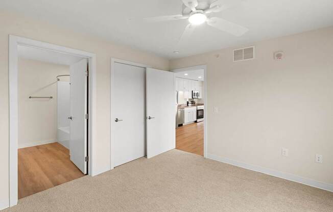 A room with a ceiling fan and a mirrored closet door.