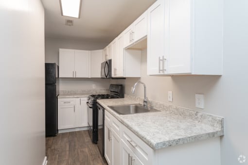 a kitchen with white cabinets and granite counter tops