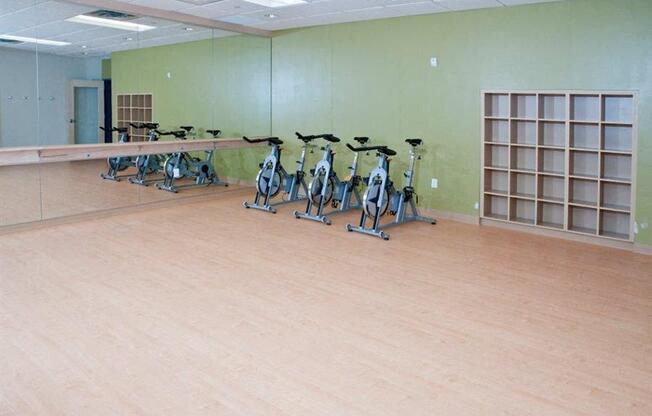 A room with exercise bikes and a shelving unit.