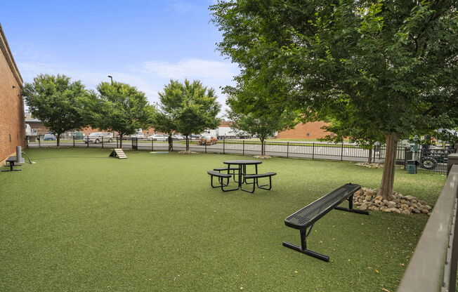 a picnic table and bench sit in a grassy area with trees and a playground in the