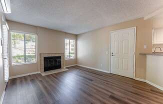 an empty living room with wood flooring and a fireplace