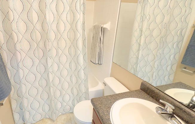 A bathroom with a toilet, sink, and shower curtain.