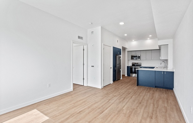 a living room and kitchen with a wood floor and white walls