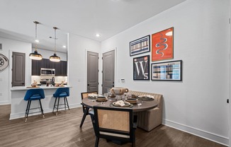 a dining area with a table and chairs and a kitchen in the background