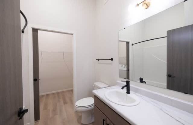 A bathroom with a toilet, sink, and mirror.