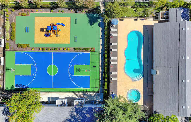 A basketball court is surrounded by a pool and a playground.
