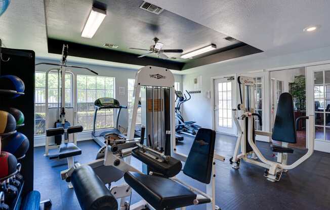 a gym with weights and other exercise equipment in a building with windows
