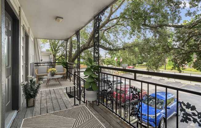 A balcony with a blue car parked on the street.