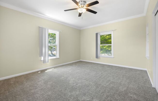 a bedroom with two windows and a ceiling fan