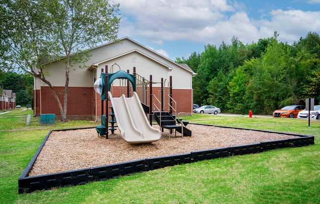 a playground with a swing set and slides in front of a house