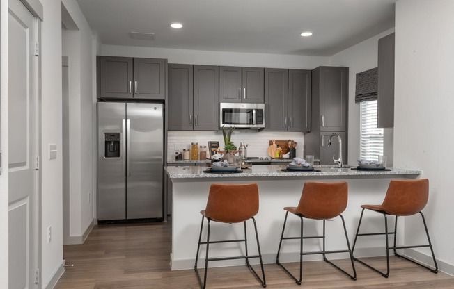 a kitchen with stainless steel appliances and a counter with three stools