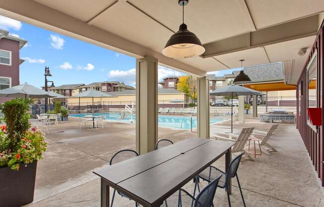 A patio with a table and chairs overlooking a pool.