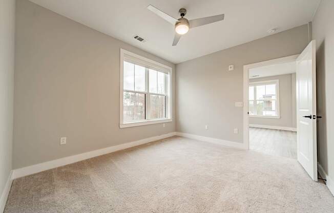 A spacious room with a ceiling fan and carpeted floor.