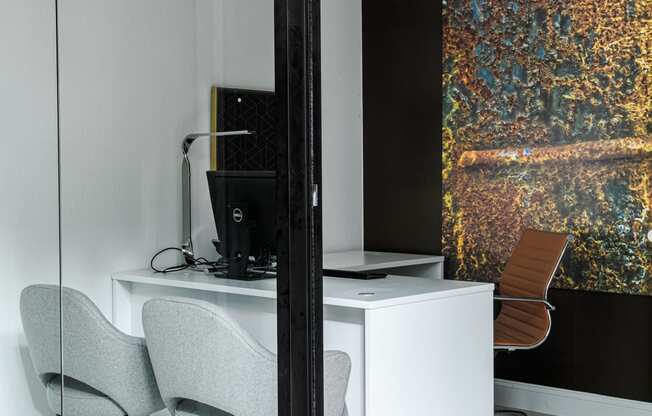 a room with a desk and two chairs and a large painting on the wall