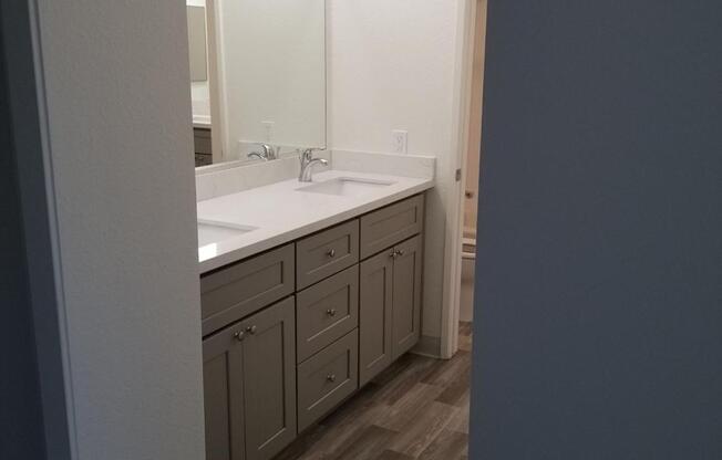 A bathroom with a sink, mirror, and cabinets.