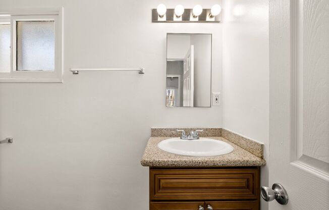 A bathroom with a sink, mirror, and wooden cabinet.