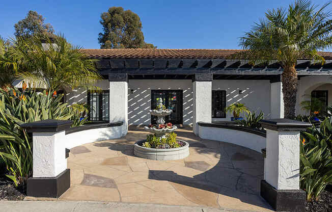 A building with a red tile roof and a fountain in front.