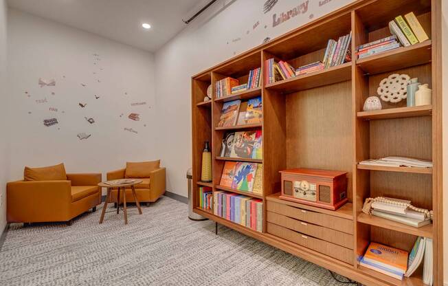 A room with a bookshelf, chairs, and a carpet.