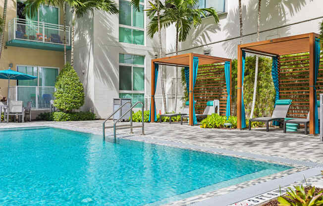 a swimming pool in front of a building with palm trees