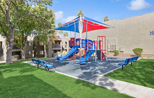 Community Playground with a Slide and Blue/Red Canopy at Saddle Ridge Apartments in Tucson, AZ.