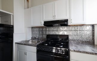 a kitchen with white cabinets and a black stove