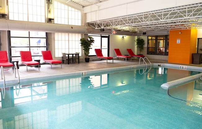 A large indoor swimming pool with red chairs and a yellow door.
