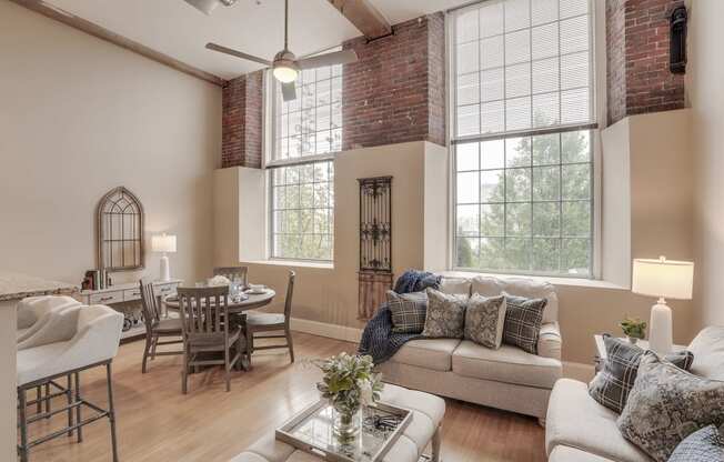 a living room with a couch and a table and a dining room with windows