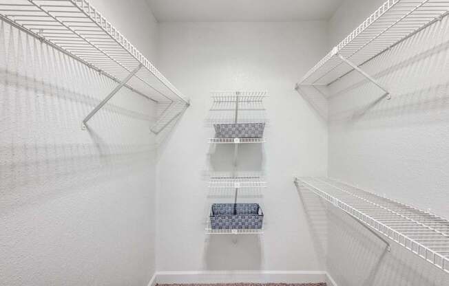 A white walk-in closet with shelves and a bench.