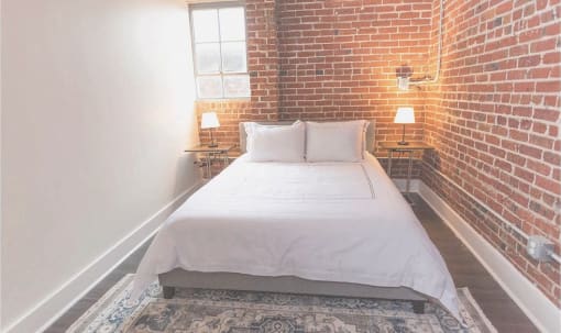 a bed in a room with a brick wall