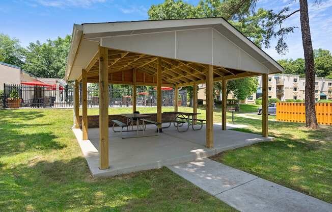 a picnic pavilion with benches and tables in a park