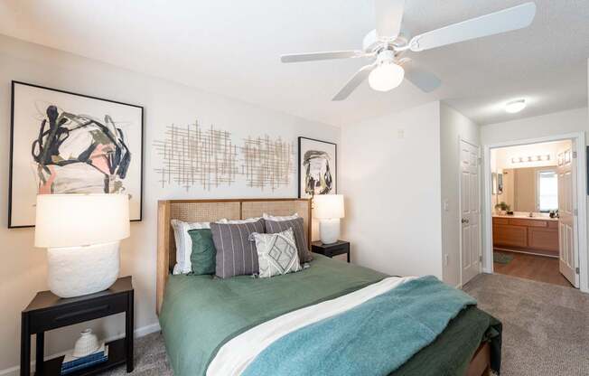 A bedroom with a bed, two lamps, and a painting on the wall.