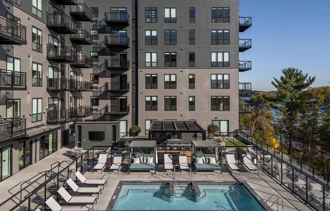 A large apartment complex with a pool and lounge chairs.