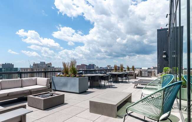 A patio with a white couch, a green chair and a fire pit.