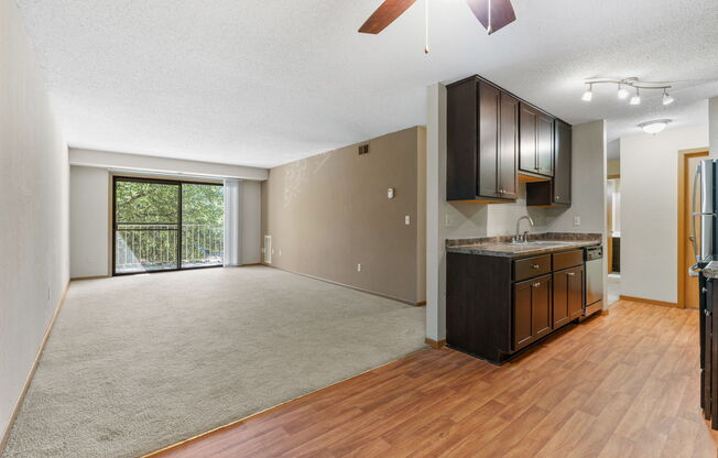 an empty living room and kitchen with wood flooring and a sliding glass door