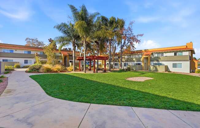 A building with a red roof is surrounded by a green lawn and palm trees.