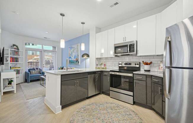 a kitchen with stainless steel appliances and white cabinets at Link Apartments® Calyx, Chapel Hill