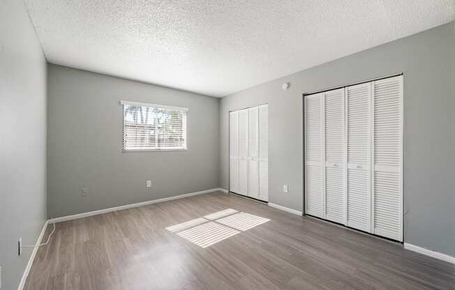 an empty living room with wood flooring and a window