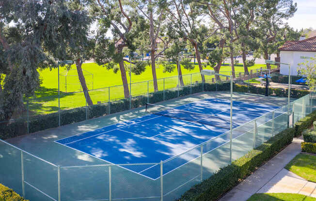 A tennis court surrounded by a fence and trees.