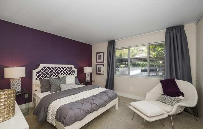 a bedroom with a purple accent wall and a white bed