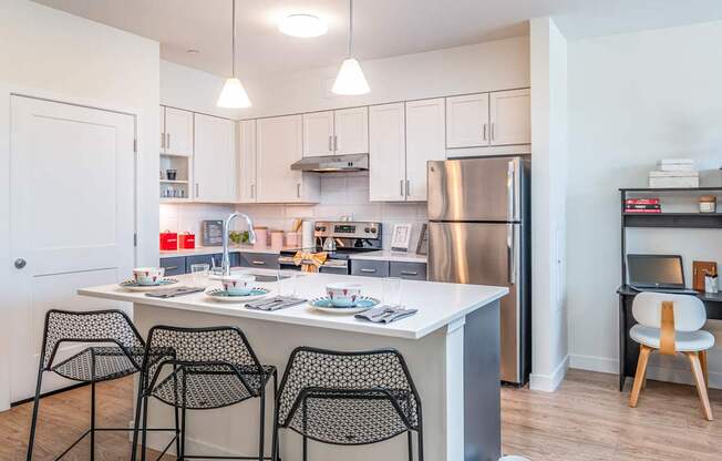 A kitchen with a table and chairs in front of it in model apartment at the Mastlight.
