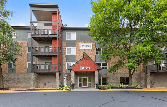 an apartment building with brick and stone exterior and trees