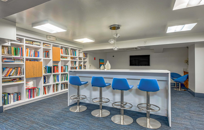 a library with a counter and chairs and shelves of books